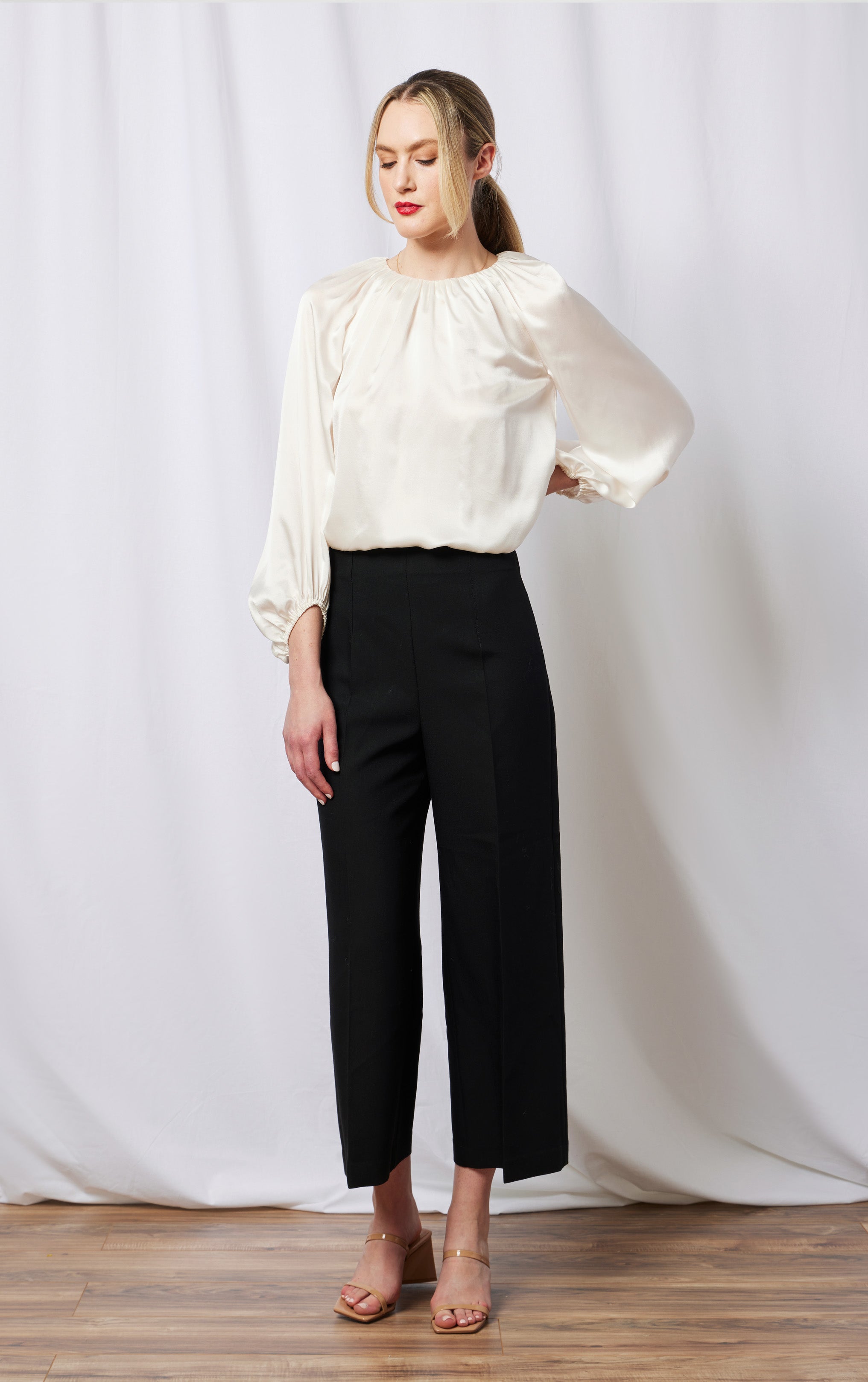 front view of woman wearing silk white top with rusched neck and puff sleeve opening