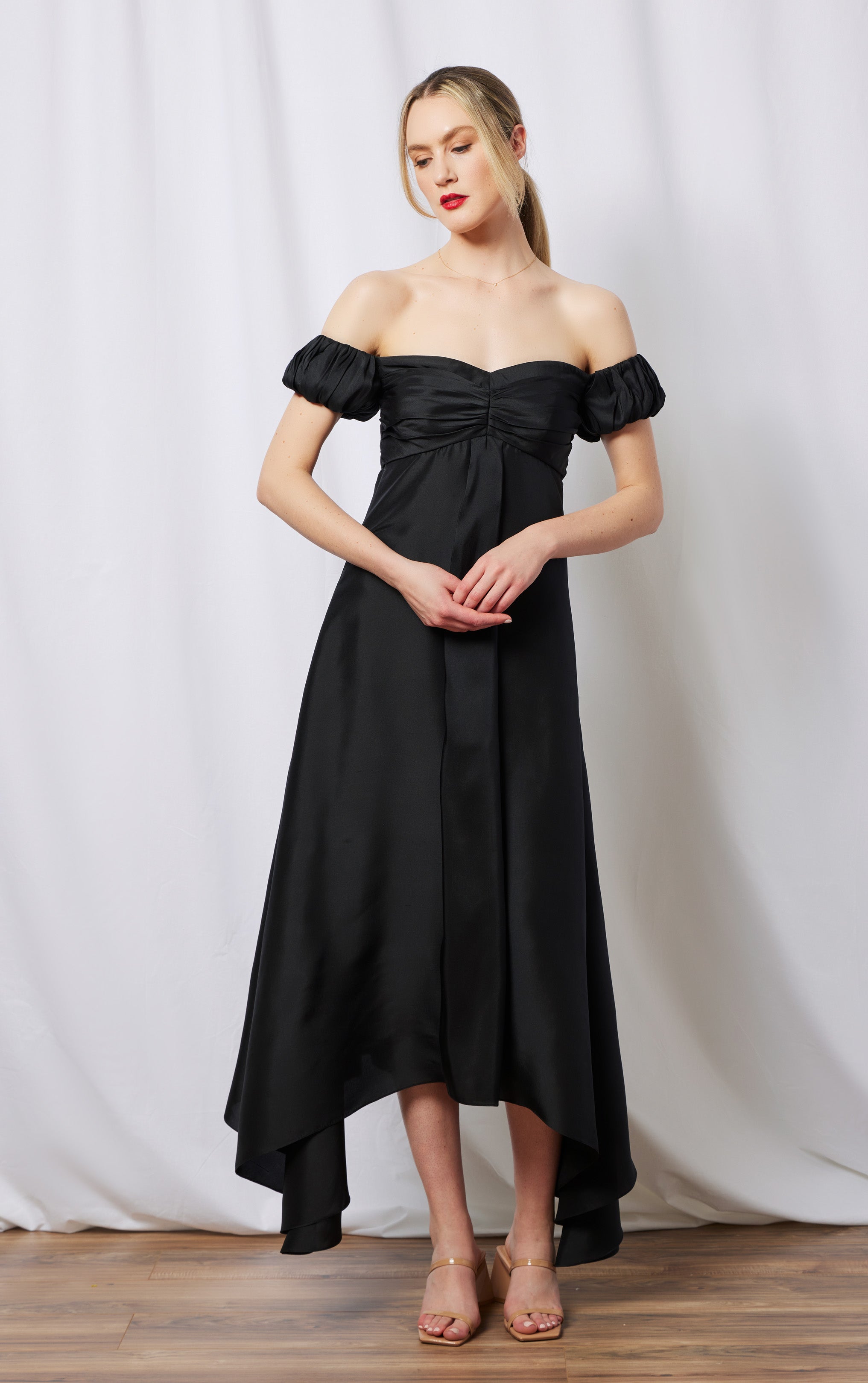 front view of woman standing wearing long silk black off the shoulder dress
