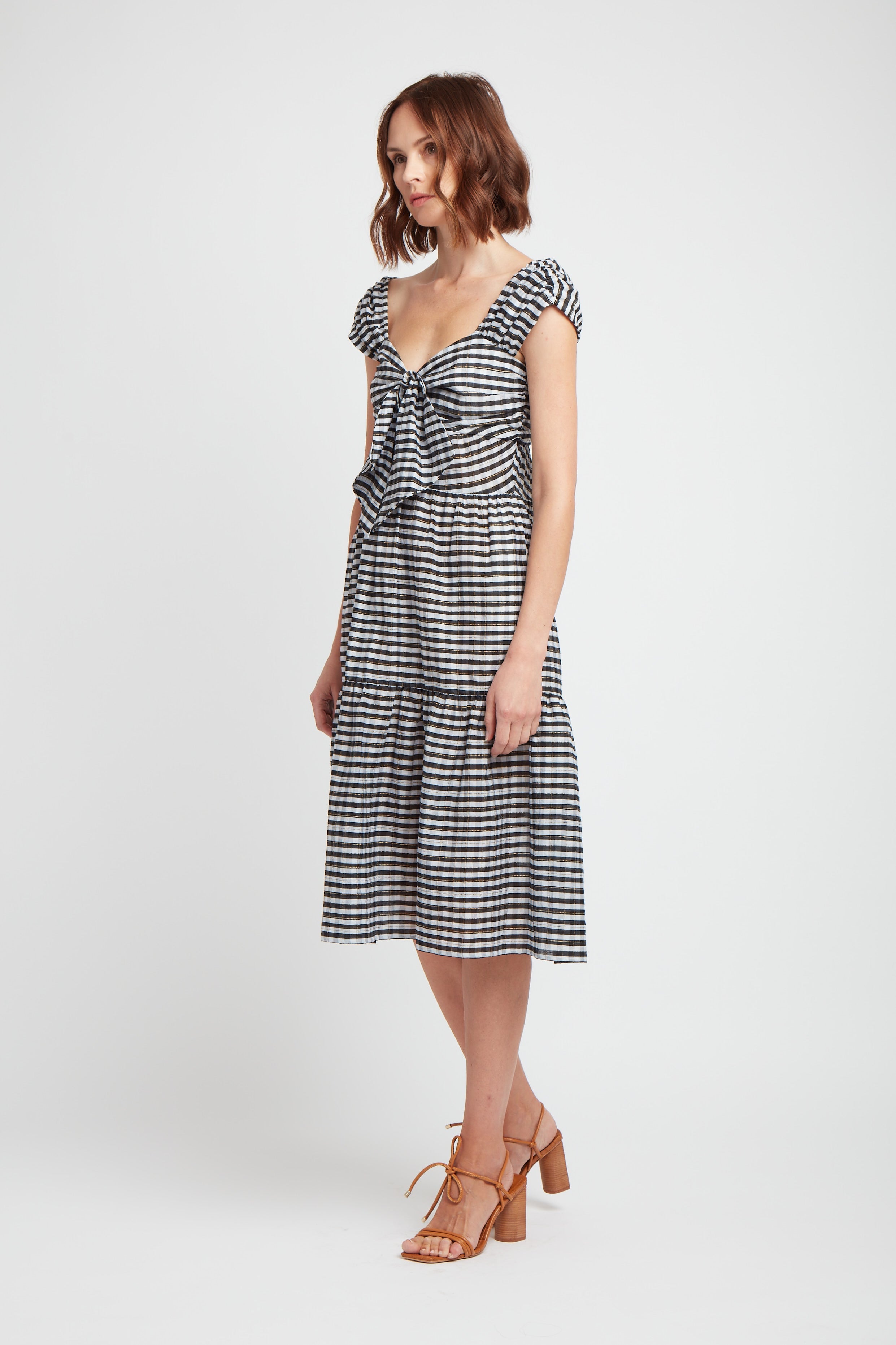 side view of black and white cotton and silk blend dress with pockets, front tie detail and rusched shoulder.