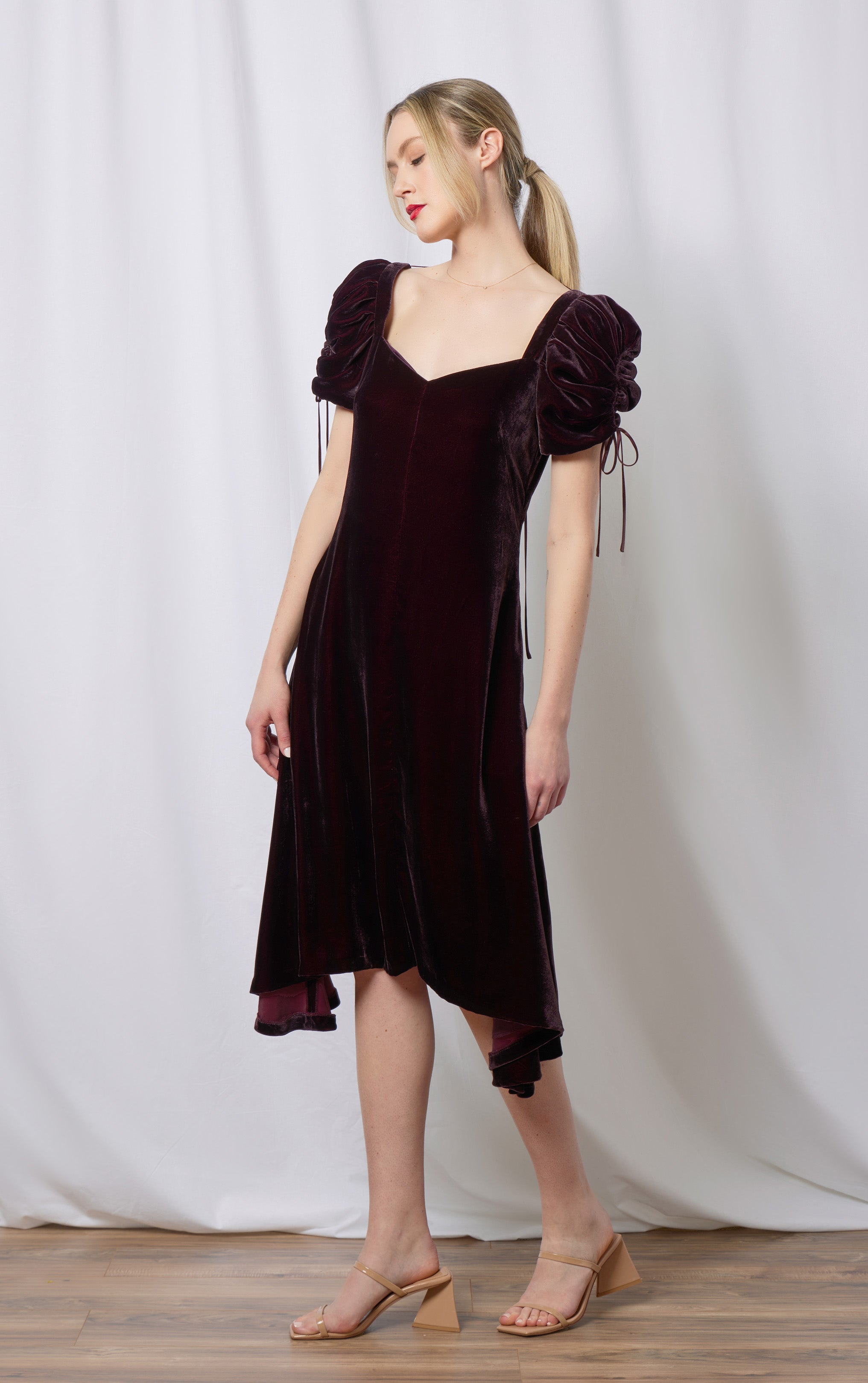 woman standing in front of curtain wearing purple silk velvet dress with puff sleeves with drawstrings and pockets