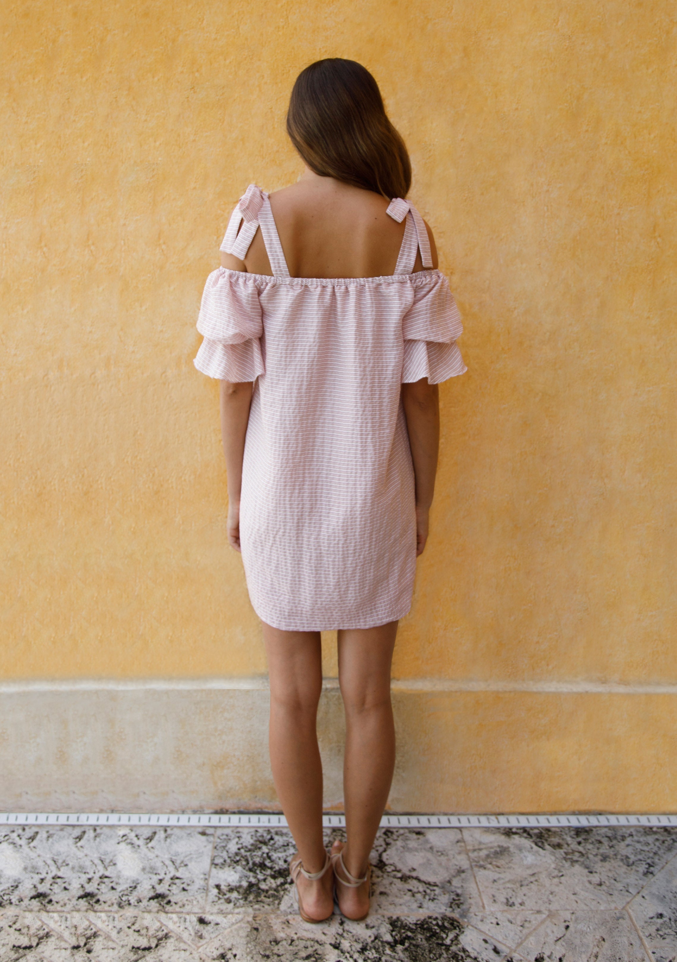 back view of woman modelling pink striped silk off the shoulder puff sleeve dress