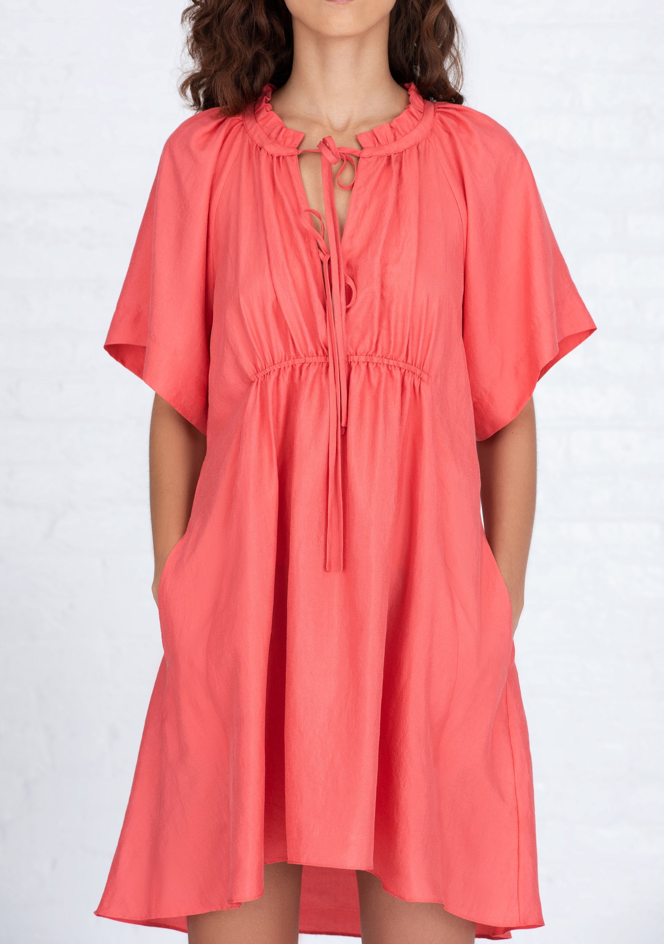front profile view of woman wearing coral short sleeved silk dress handwoven