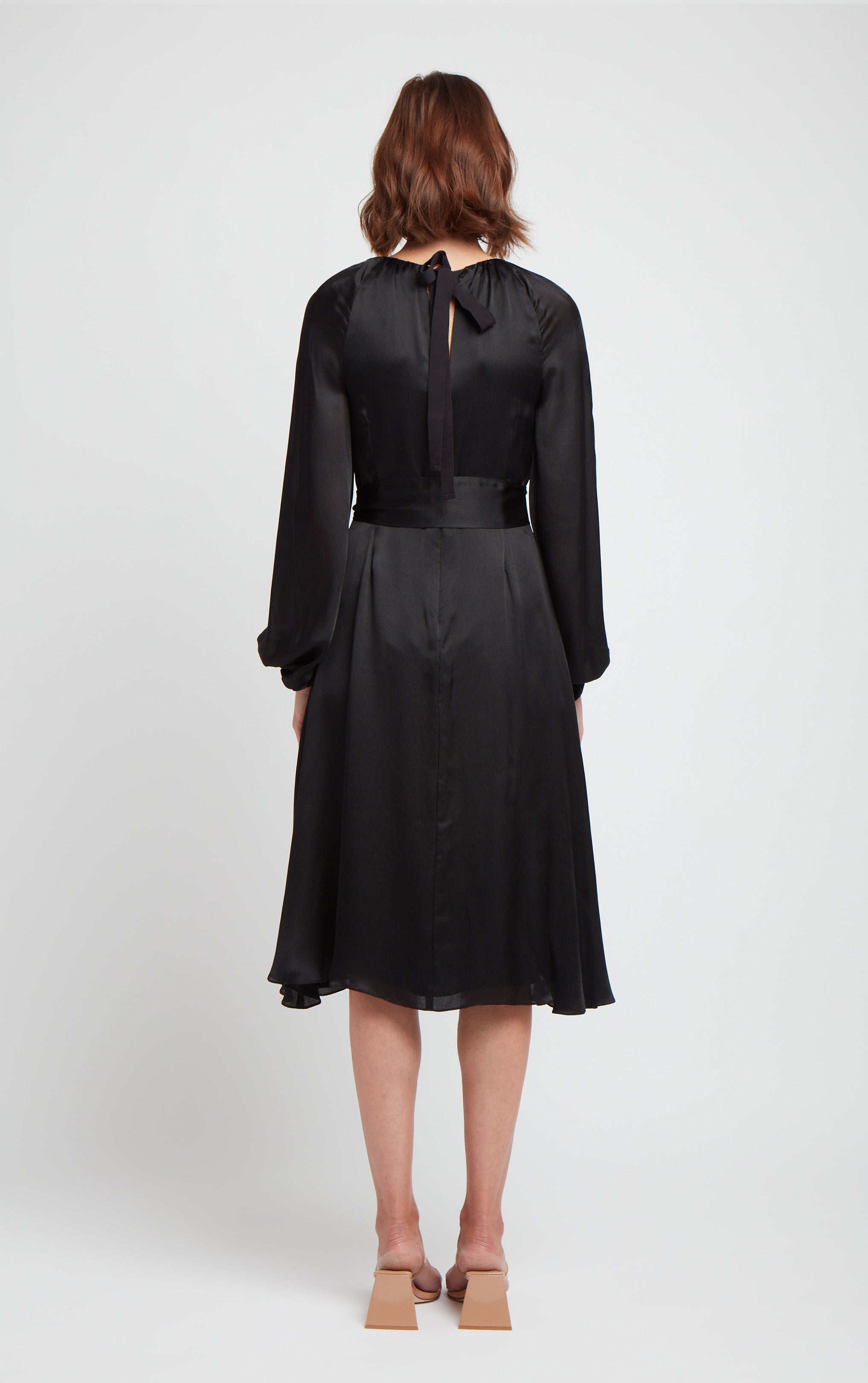 back view of woman wearing black puff sleeve silk dress with rusched neck