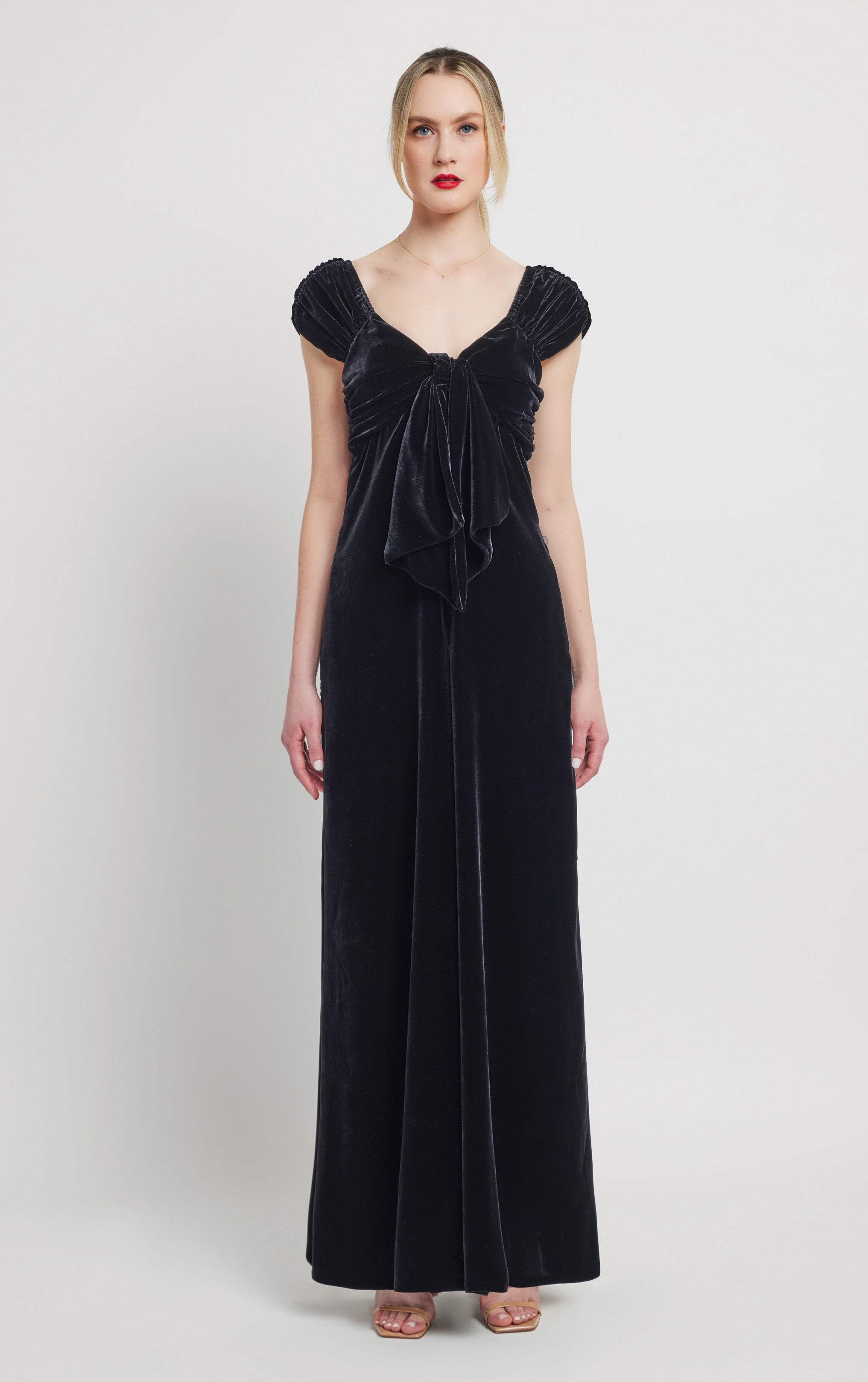 woman standing wearing silk velvet black jumpsuit with front bow