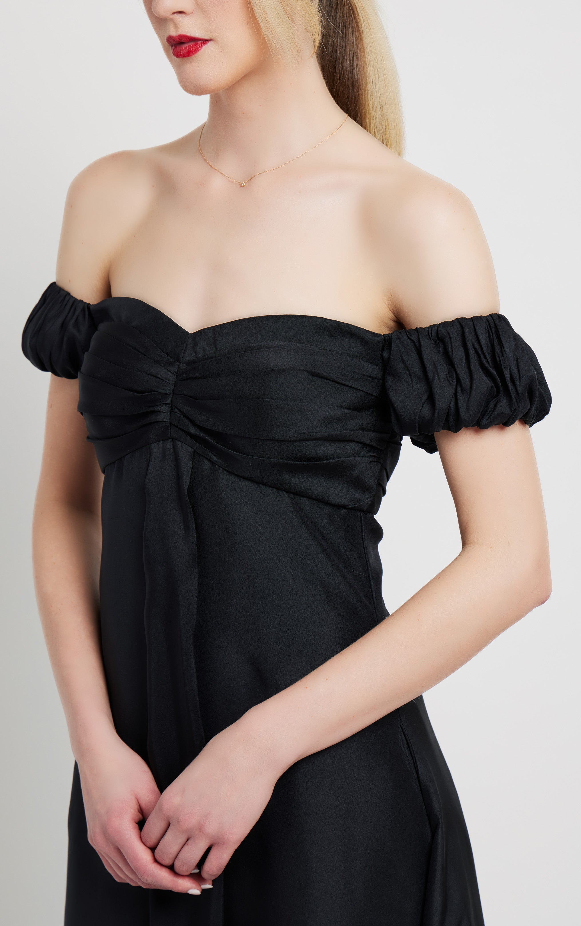 close up front profile of woman wearing long silk black off the shoulder dress