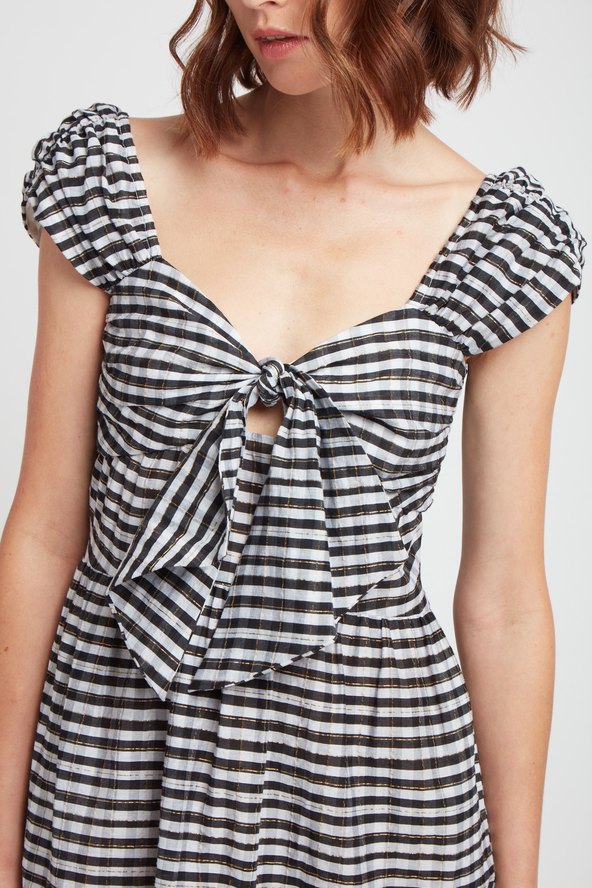 close up view of black and white cotton and silk blend dress with pockets, front tie detail and rusched shoulder.