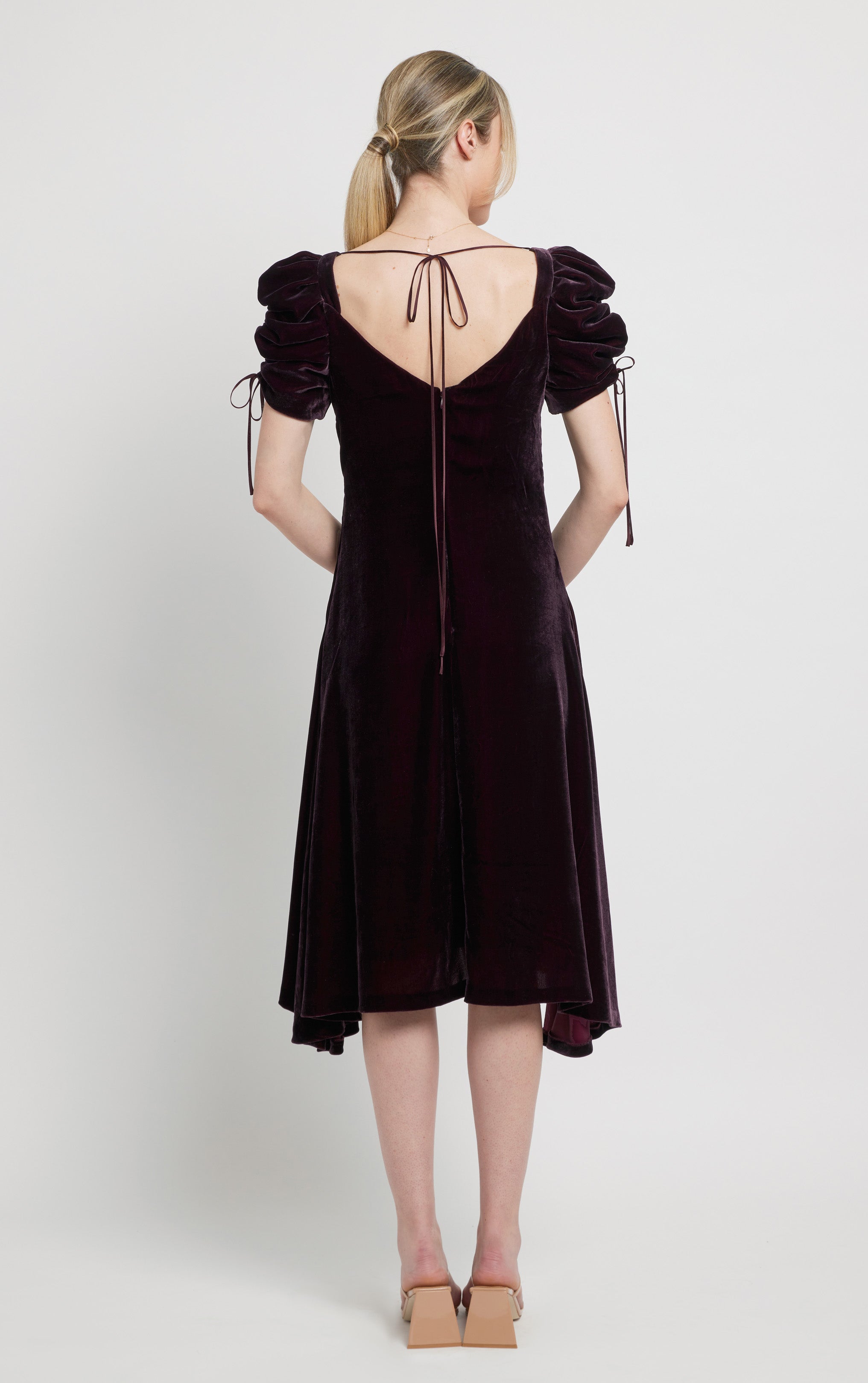 back view of woman wearing purple silk velvet dress with puff sleeves with drawstrings