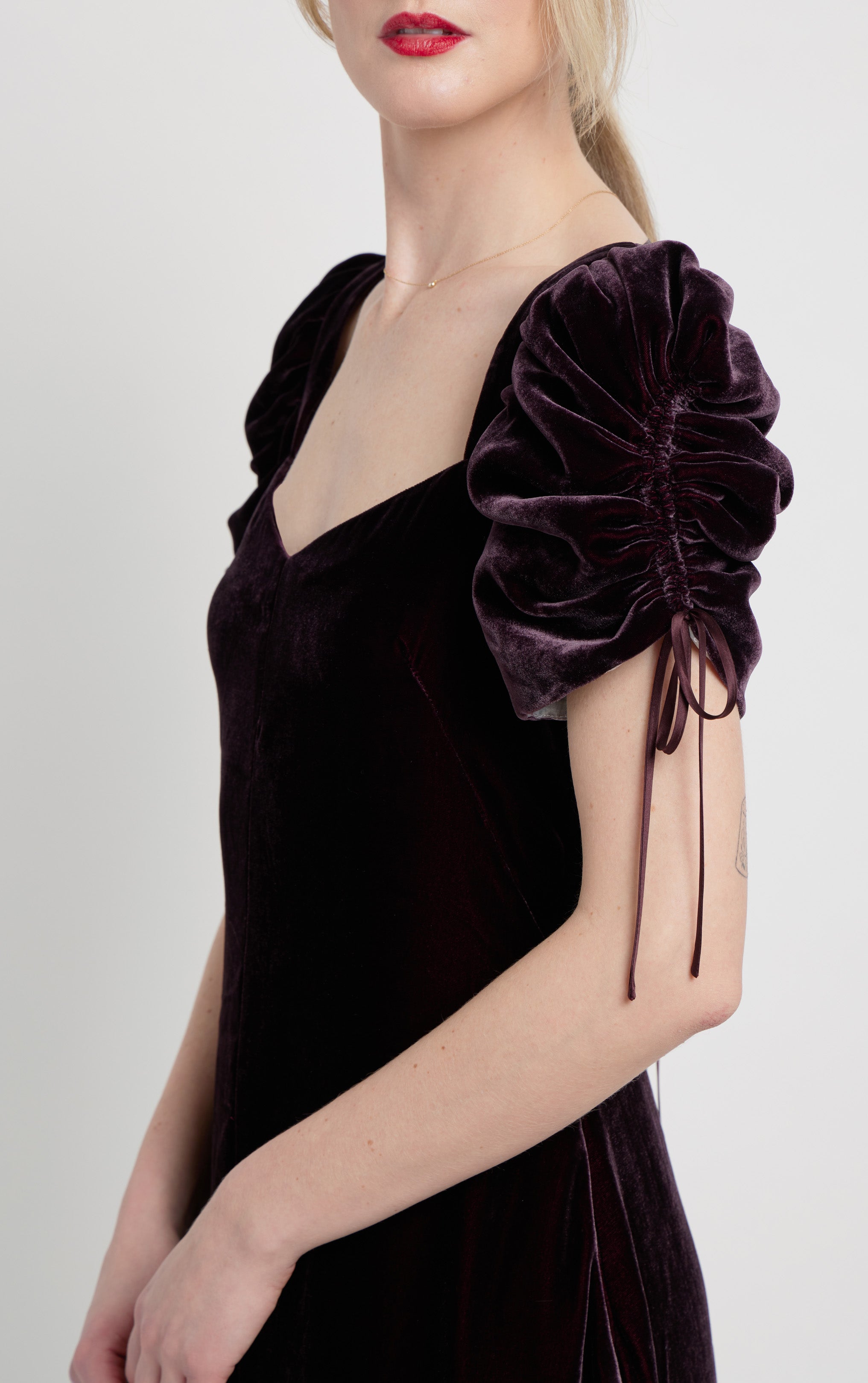side close up view of woman wearing purple silk velvet dress with puff sleeves with drawstrings and pockets