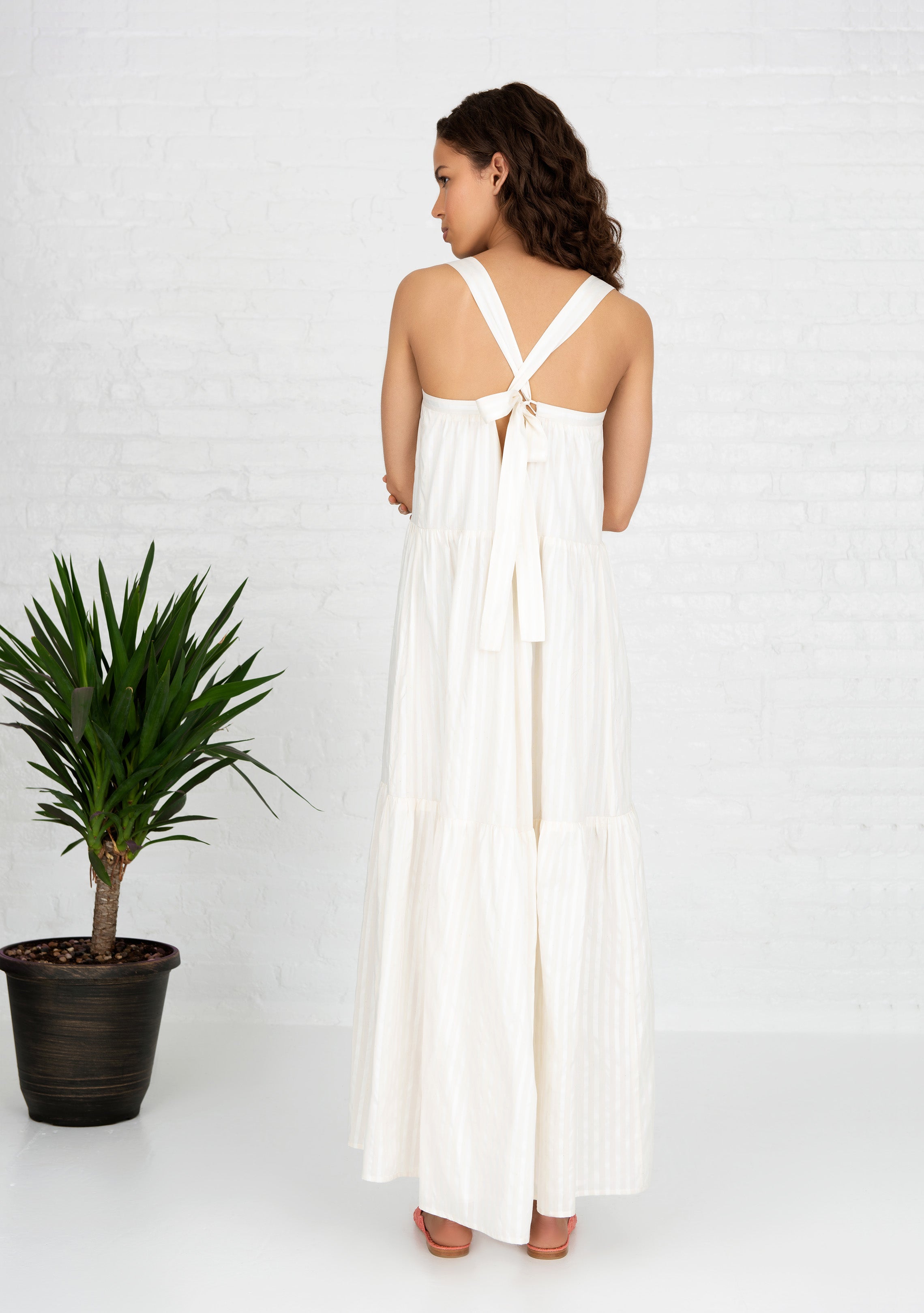 full back profile view of woman wearing white sleeveless cotton silk blend dress