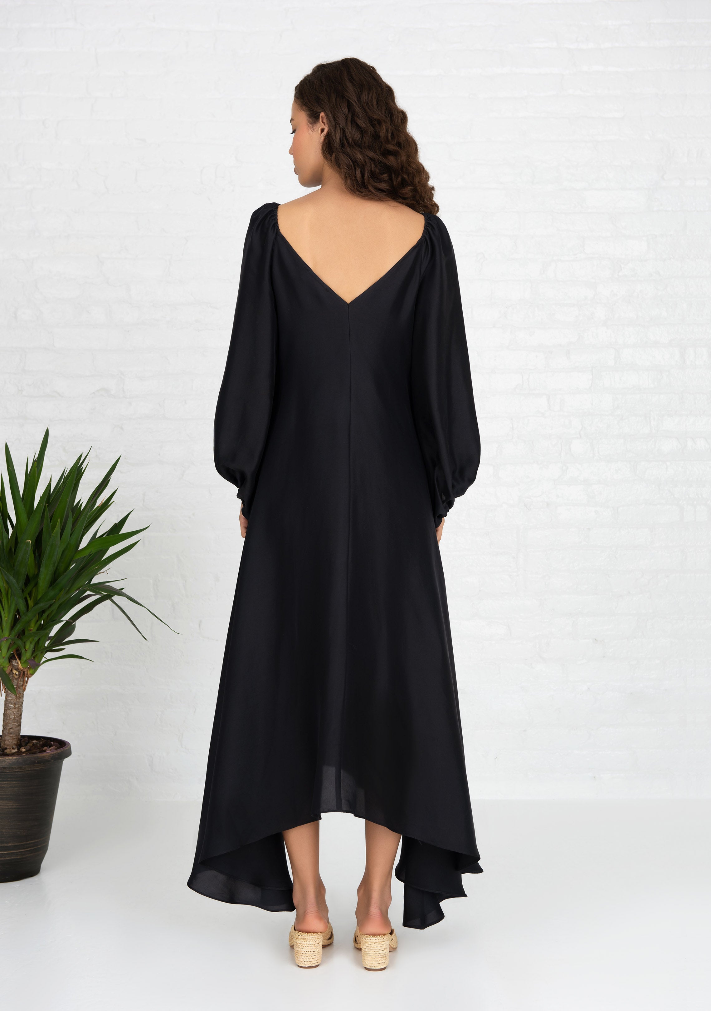 back view of woman wearing black puff sleeve silk dress front and back v neck with heels