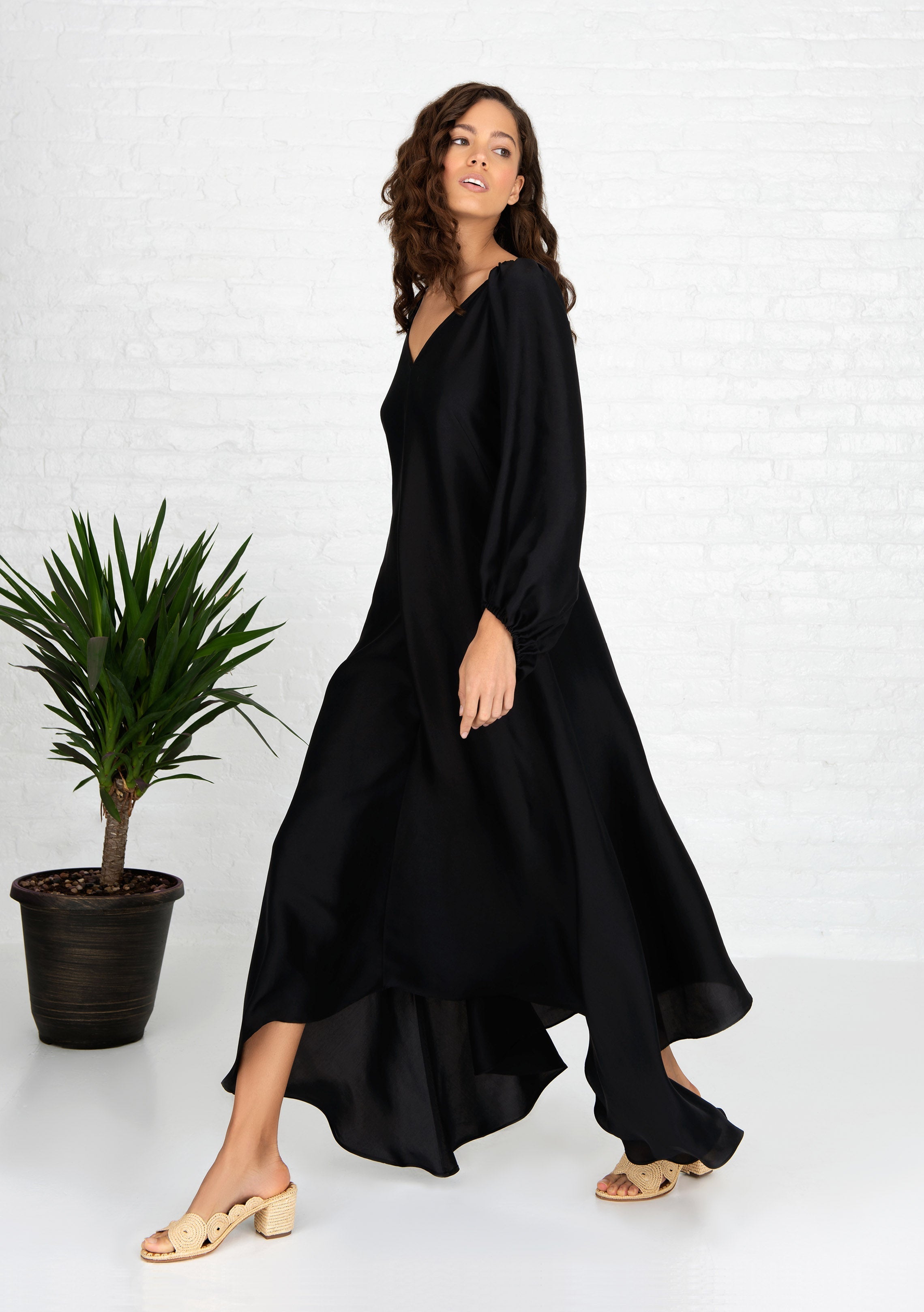 woman standing wearing black puff sleeve silk dress front and back v neck with heels