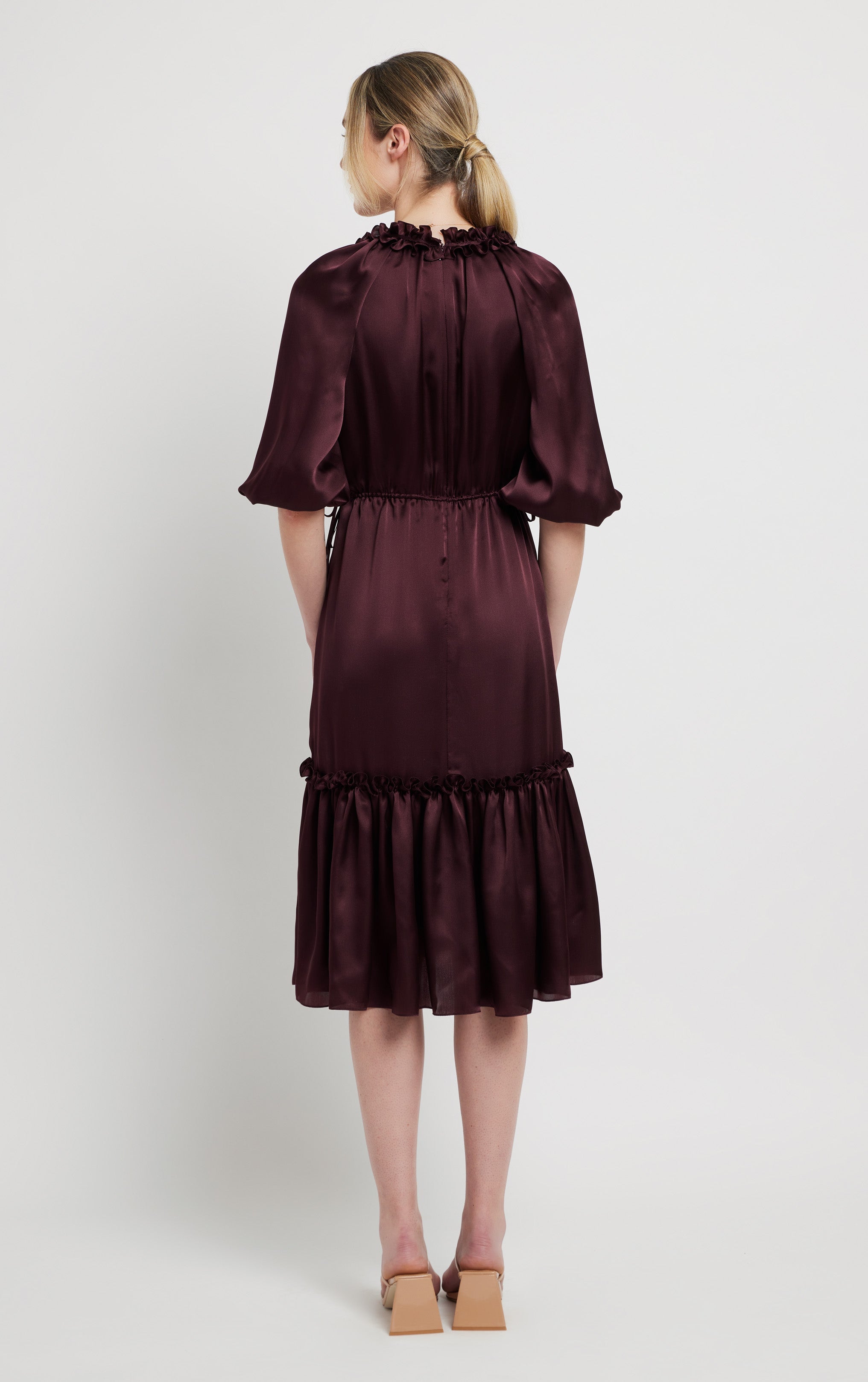 back view of woman wearing burgundy silk dress with invisible zipper ruffled neck and puffed sleeves