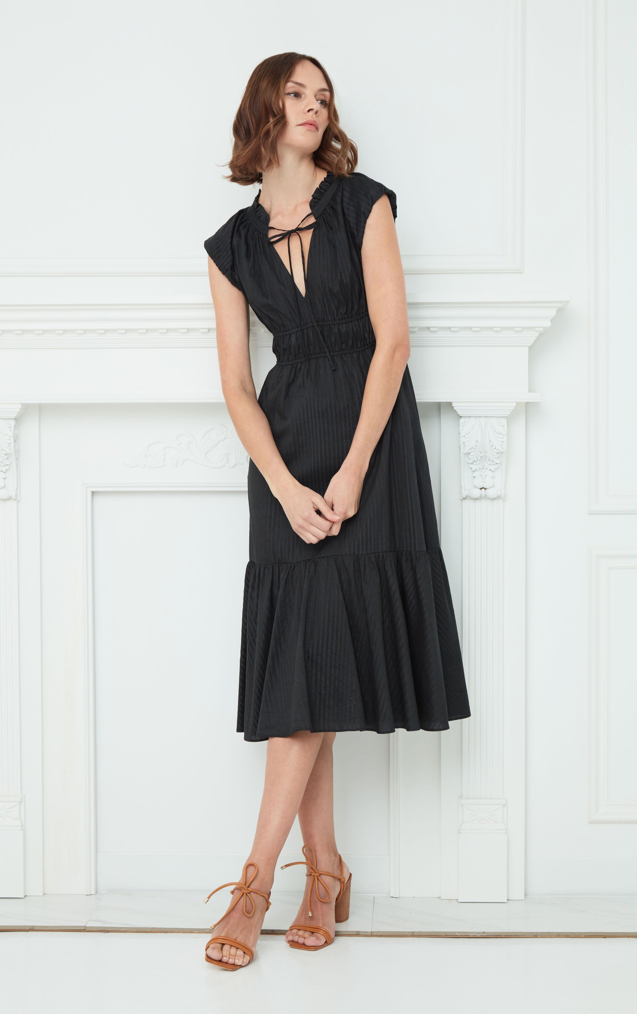 woman standing wearing black sleeveless cotton silk blend dress with tie in front